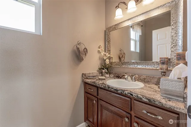 a bathroom with a granite countertop sink and a mirror