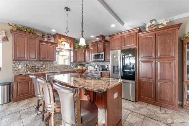 a kitchen with stainless steel appliances granite countertop a sink a stove a refrigerator and cabinets