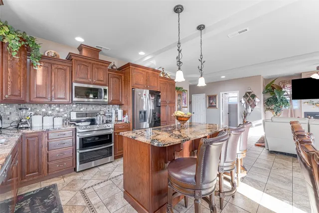 a kitchen with stainless steel appliances kitchen island granite countertop a stove a sink a dining table and chairs with wooden floor