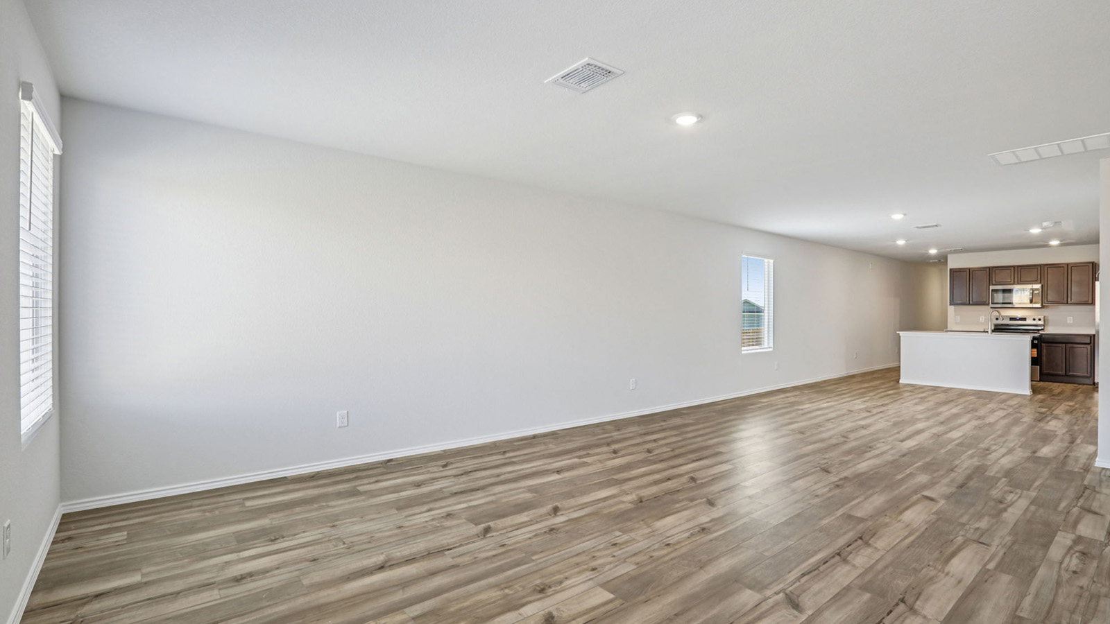 156 Wyatt Way Jarrell, TX 76537 - Photo 13 of 30 Spacious open-concept room featuring wood-finish flooring, white walls, and recessed lighting