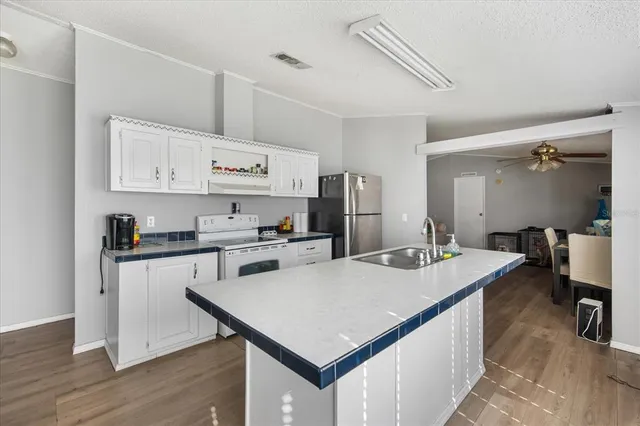 a kitchen with a stove a sink dishwasher and a refrigerator with wooden floor