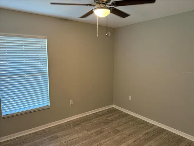 en empty room with wooden floor and fan