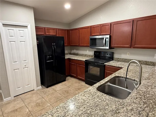 a kitchen with stainless steel appliances granite countertop a refrigerator and a sink