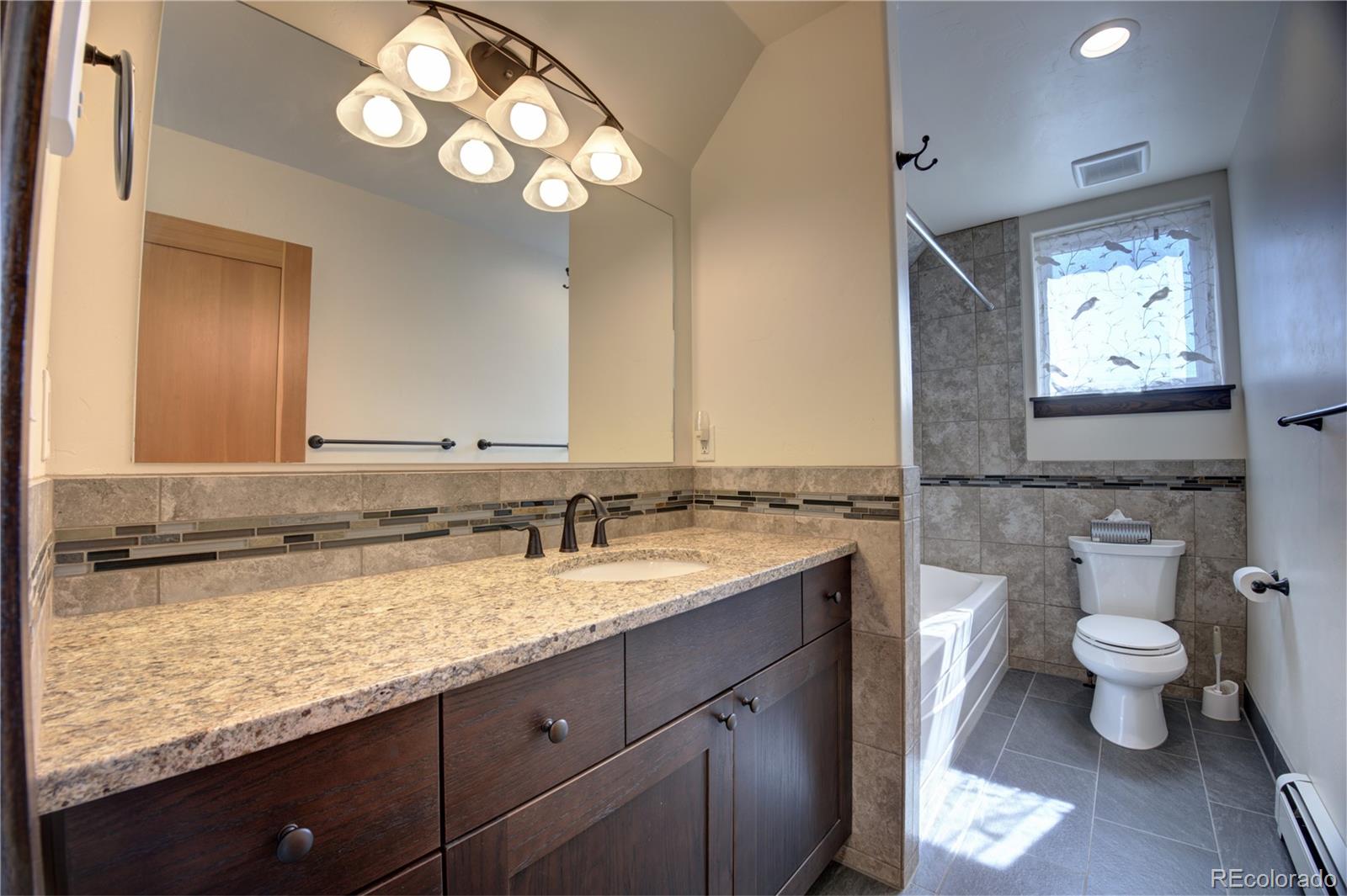 315 G Street Salida, CO 81201 - Photo 24 of 43 a bathroom with a granite countertop sink a toilet and a mirror
