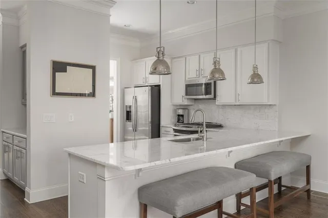 a kitchen with stainless steel appliances granite countertop a sink a microwave refrigerator and chairs