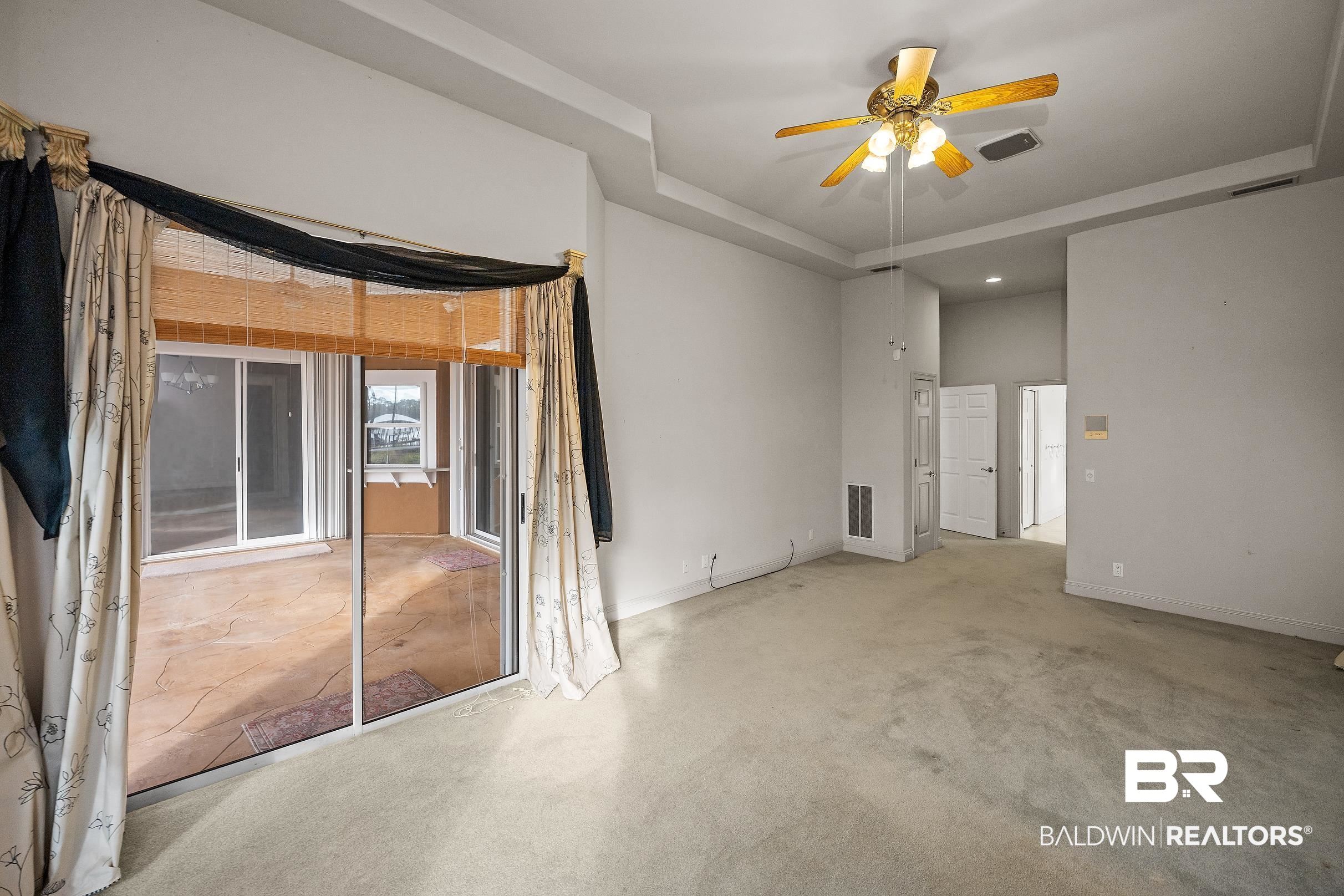8591 Bay Harbor Road Elberta, AL 36530 - Photo 31 of 56 Spare room featuring a tray ceiling, ceiling fan, and carpet flooring