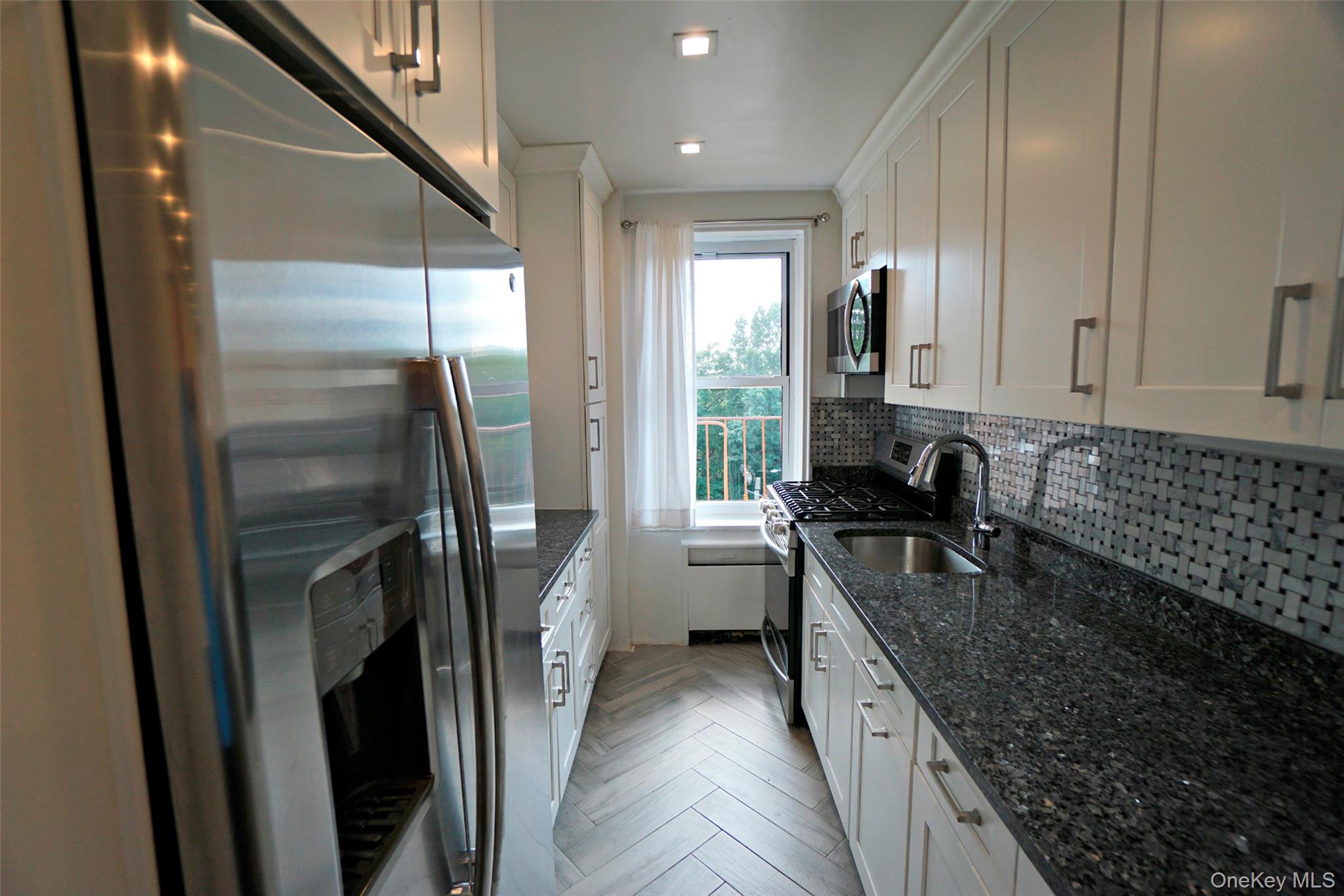 7281 113th Street, Unit 5F Queens, NY 11375 - Photo 4 of 22 a kitchen with stainless steel appliances granite countertop a refrigerator a sink a stove and white cabinets