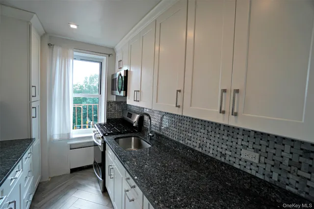a kitchen with granite countertop a sink a stove and cabinets