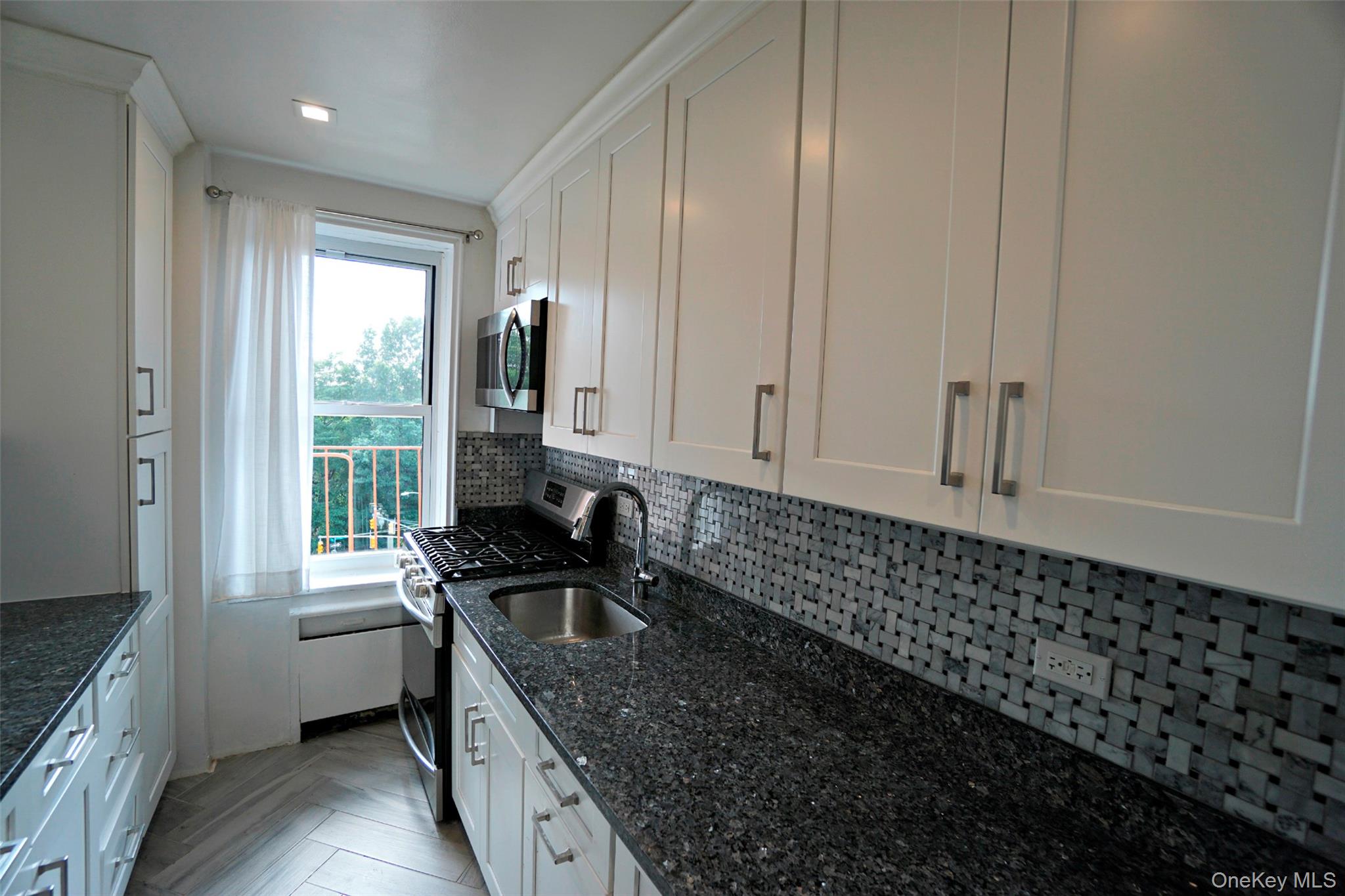 7281 113th Street, Unit 5F Queens, NY 11375 - Photo 6 of 22 a kitchen with granite countertop a sink a stove and cabinets