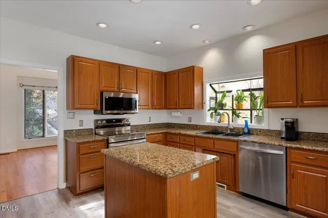 a kitchen with stainless steel appliances granite countertop wooden cabinets a stove top oven a sink and dishwasher with wooden floor