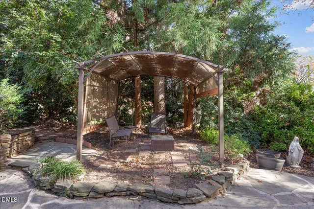 a view of a small yard in front of a house with large trees