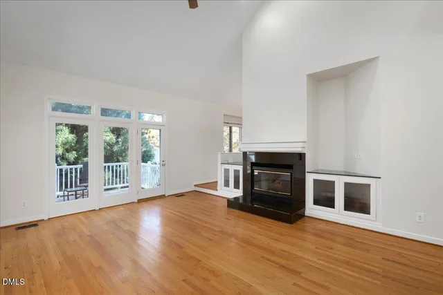 a view of an empty room with wooden floor fireplace and a window