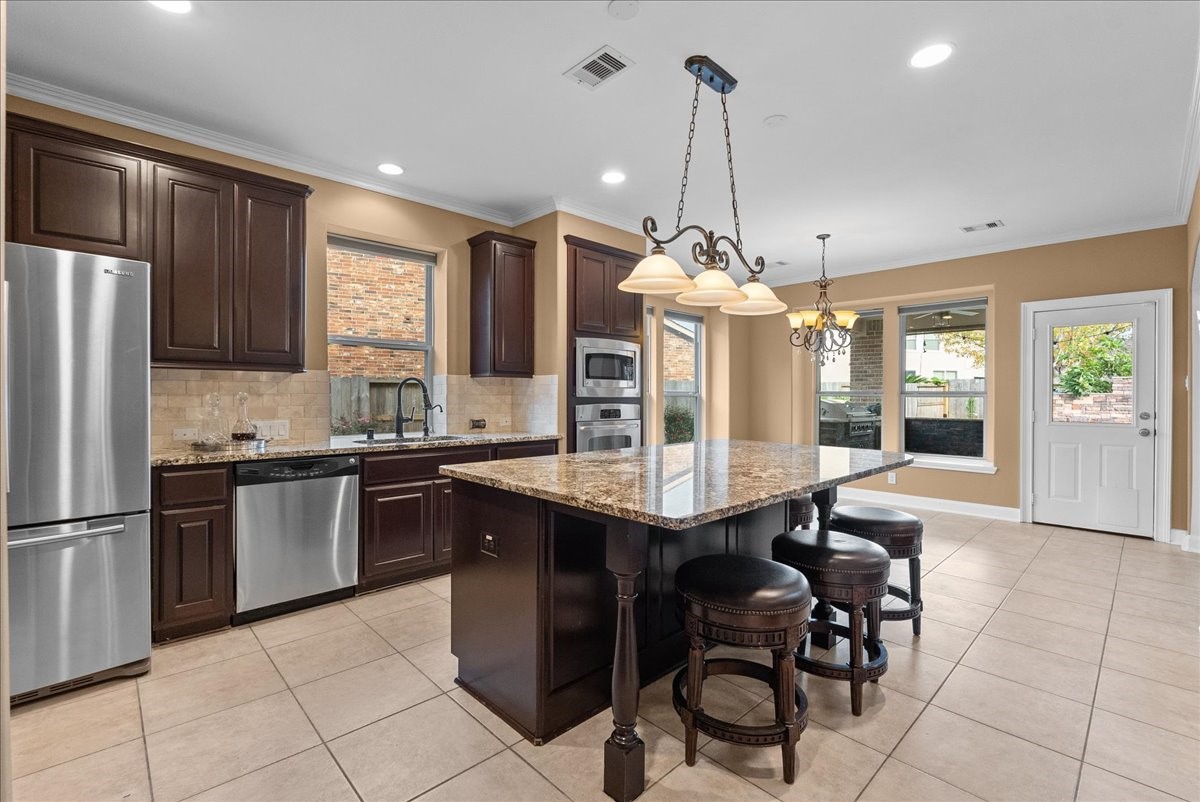 1358 Porta Rosa Lane League City, TX 77573 - Photo 6 of 48 An eat-in island kitchen showcases granite countertops, stainless steel appliances, and 42" cabinetry finished with crown molding.