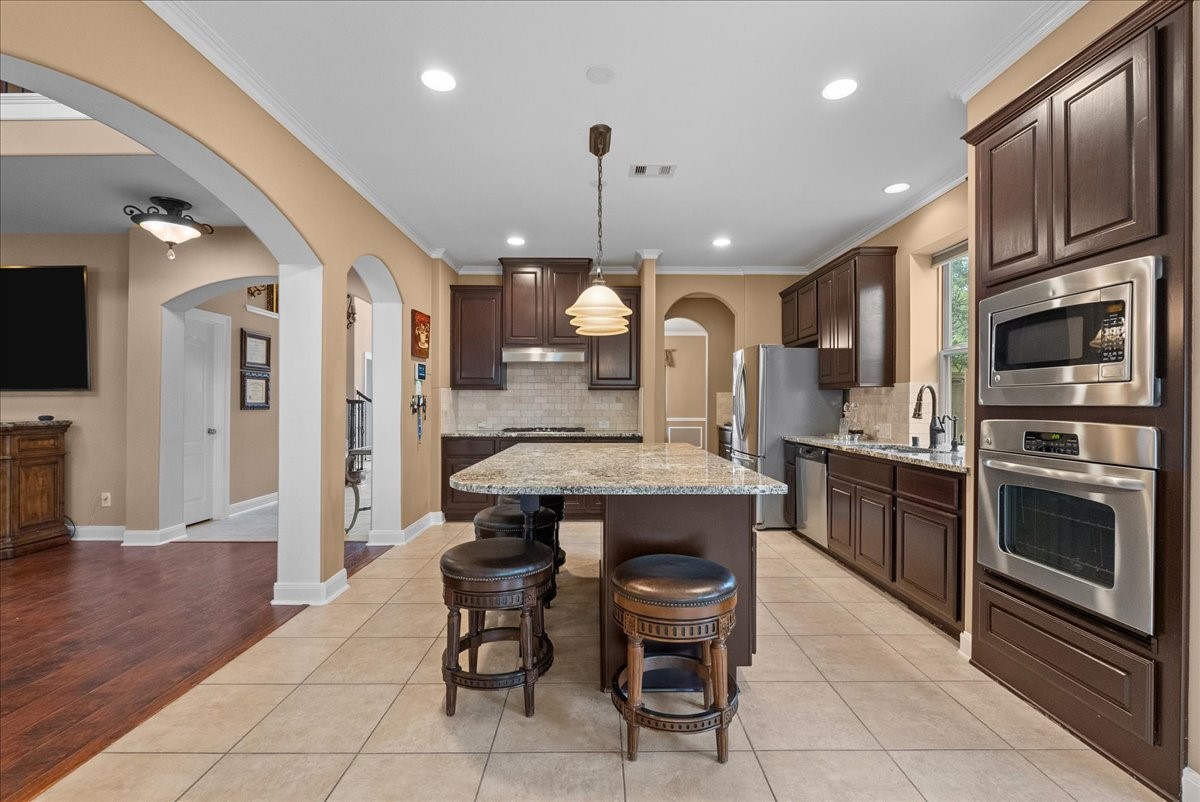 1358 Porta Rosa Lane League City, TX 77573 - Photo 8 of 48 An eat-in island kitchen showcases granite countertops, stainless steel appliances, and 42" cabinetry finished with crown molding.