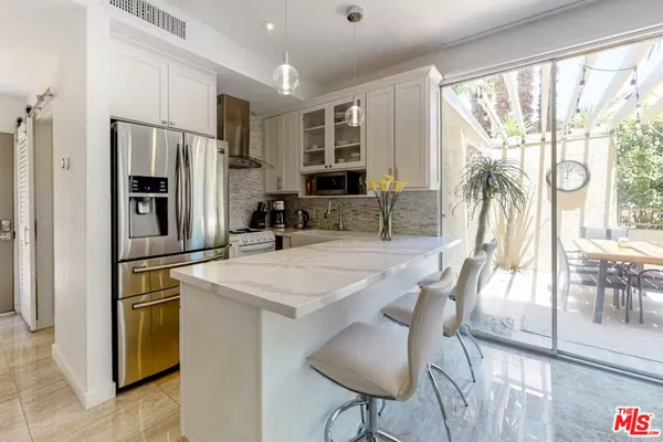 a kitchen with stainless steel appliances granite countertop a stove a refrigerator a kitchen island a dining table and chairs with wooden floor