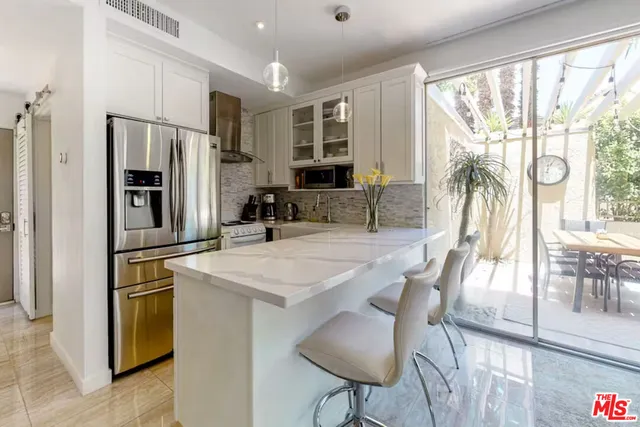 a kitchen with stainless steel appliances granite countertop a stove a refrigerator a kitchen island a dining table and chairs with wooden floor