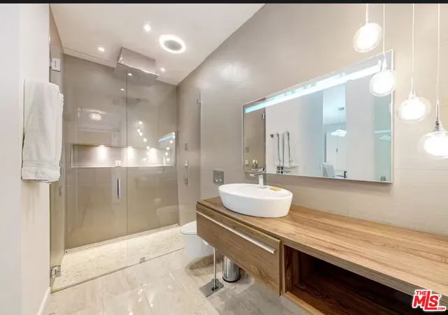 a bathroom with a sink a toilet a large mirror and shower