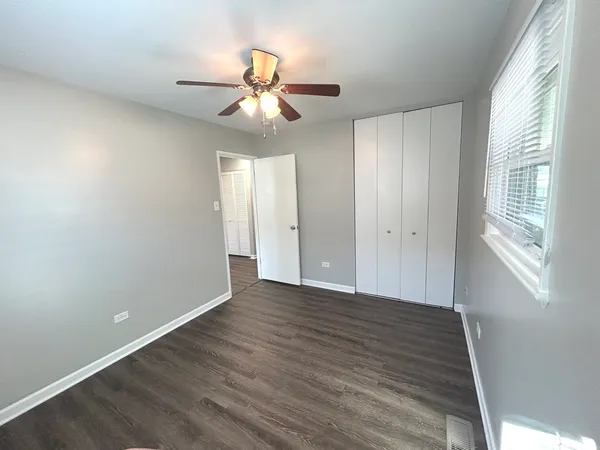 an empty room with wooden floor fan and windows