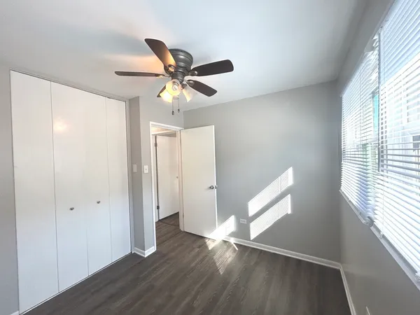 a view of empty room with wooden floor and fan