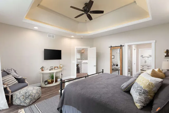 a bedroom with a bed a couch and a flat screen tv