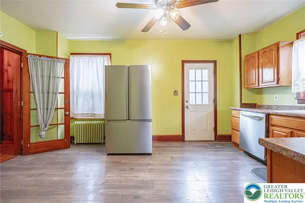 a kitchen with stainless steel appliances granite countertop white cabinets a sink dishwasher and a stove with wooden floor