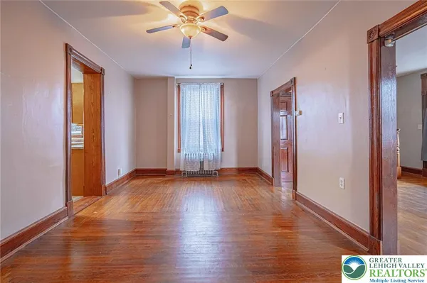 an empty room with wooden floor and a ceiling fan