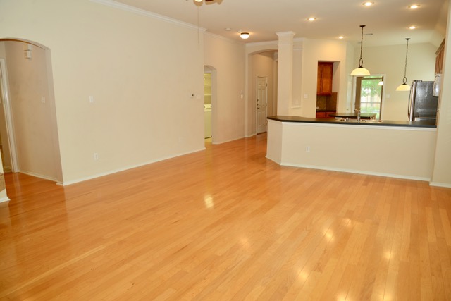 138 Chestnut Court Georgetown, TX 78633 - Photo 17 of 25 Blonde hardwood floors flow through this open-concept space, connecting the living area to a modern kitchen.