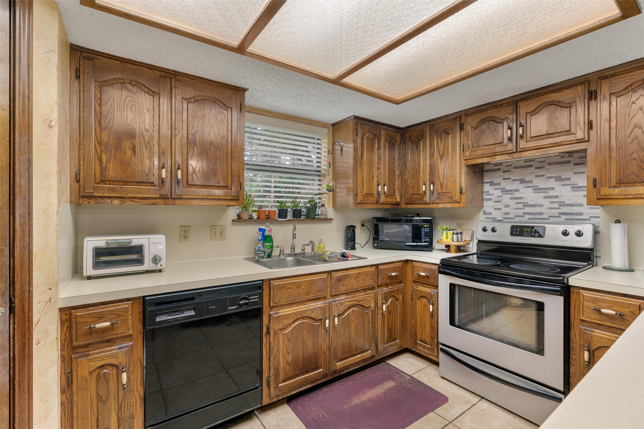 401 Drake Lane Taylor, TX 76574 - Photo 10 of 31 Kitchen featuring wood cabinetry, solid surface countertops, tile flooring, and a stainless steel and black electric range