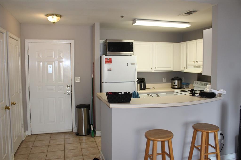 1101 Juniper Street Northeast, Unit 1416 Atlanta, GA 30309 - Photo 9 of 48 a kitchen with stainless steel appliances a stove top oven a refrigerator a sink and white cabinets