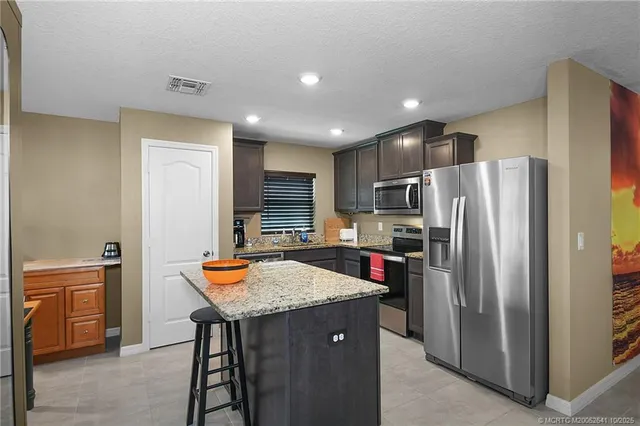 a kitchen with stainless steel appliances granite countertop a refrigerator a sink and a stove