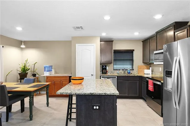 a kitchen with stainless steel appliances granite countertop a table chairs sink refrigerator and microwave