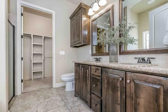 a spacious bathroom with a granite countertop sink a toilet and a mirror