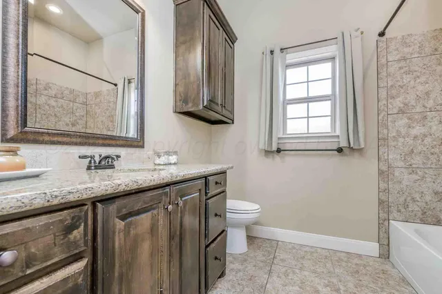 a bathroom with a granite countertop sink toilet and mirror