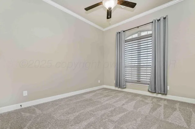 an empty room with chandelier fan and windows