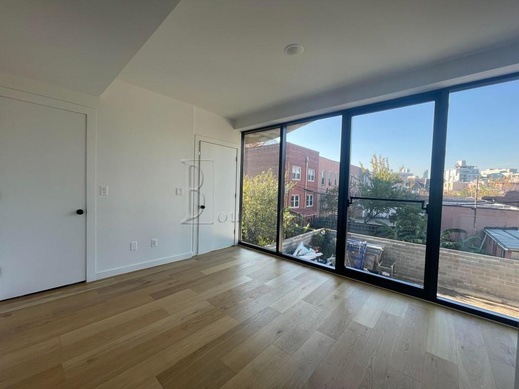 an empty room with wooden floor and windows with view