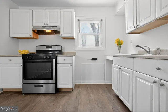 a kitchen with stainless steel appliances white cabinets and a stove top oven