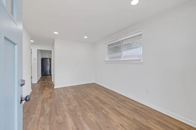 a view of an empty room with wooden floor and a window