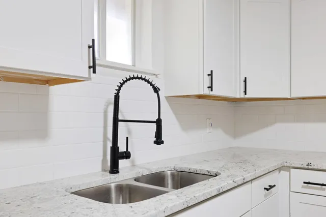a kitchen with stainless steel appliances granite countertop a sink and a white cabinets
