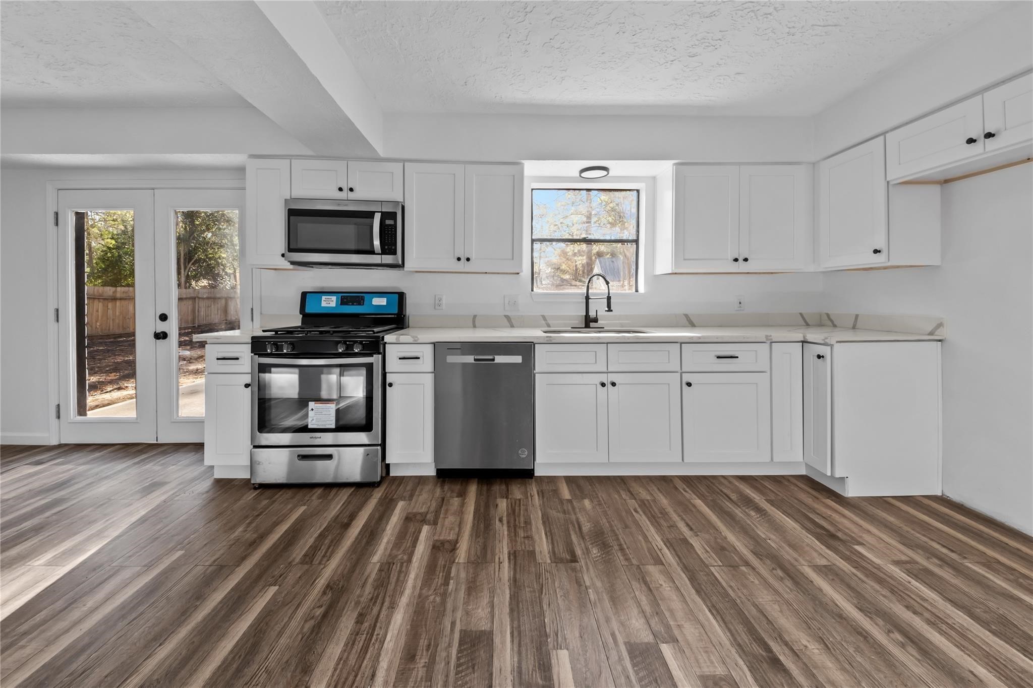 6611 Falling Waters Drive Spring, TX 77379 - Photo 12 of 16 a kitchen with stainless steel appliances granite countertop a stove top oven a sink dishwasher and a refrigerator with wooden floor