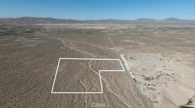 a view of a dry yard with mountains in the background