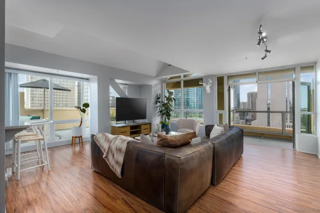 a living room with furniture large windows and wooden floor