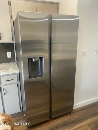 a kitchen with a refrigerator and wooden floor