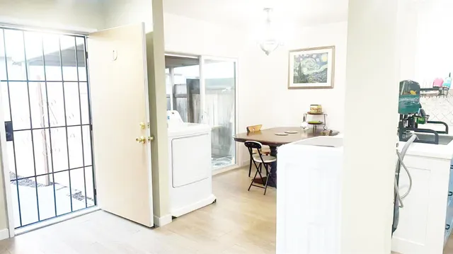 a living room with a table chairs and refrigerator