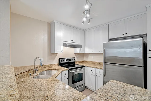 a kitchen with stainless steel appliances granite countertop a stove sink and cabinets