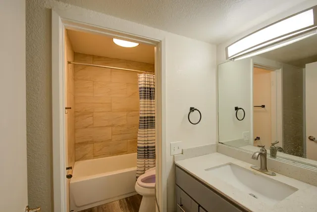 a bathroom with a granite countertop sink toilet and shower