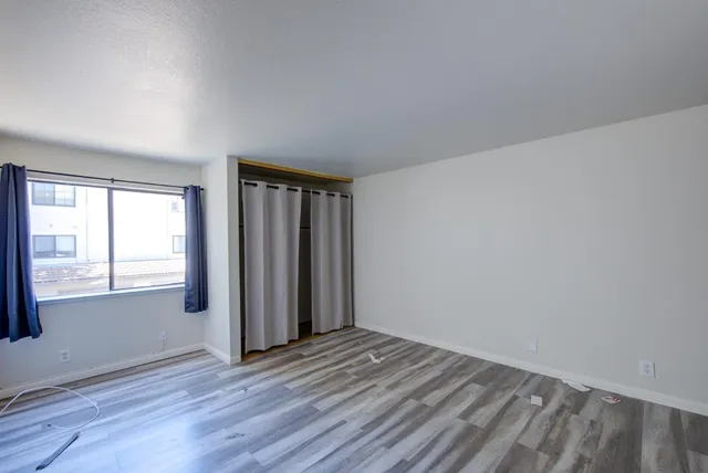 an empty room with wooden floor and windows