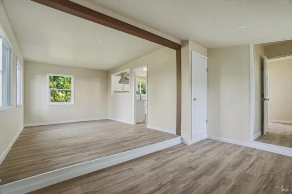 a view of an empty room with window and wooden floor