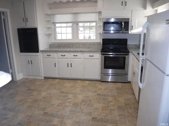 a kitchen with granite countertop a refrigerator stove and microwave
