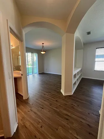 a view of a hallway with wooden floor and a living room