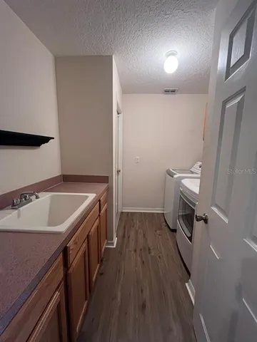 a room with a sink a toilet and wooden floor